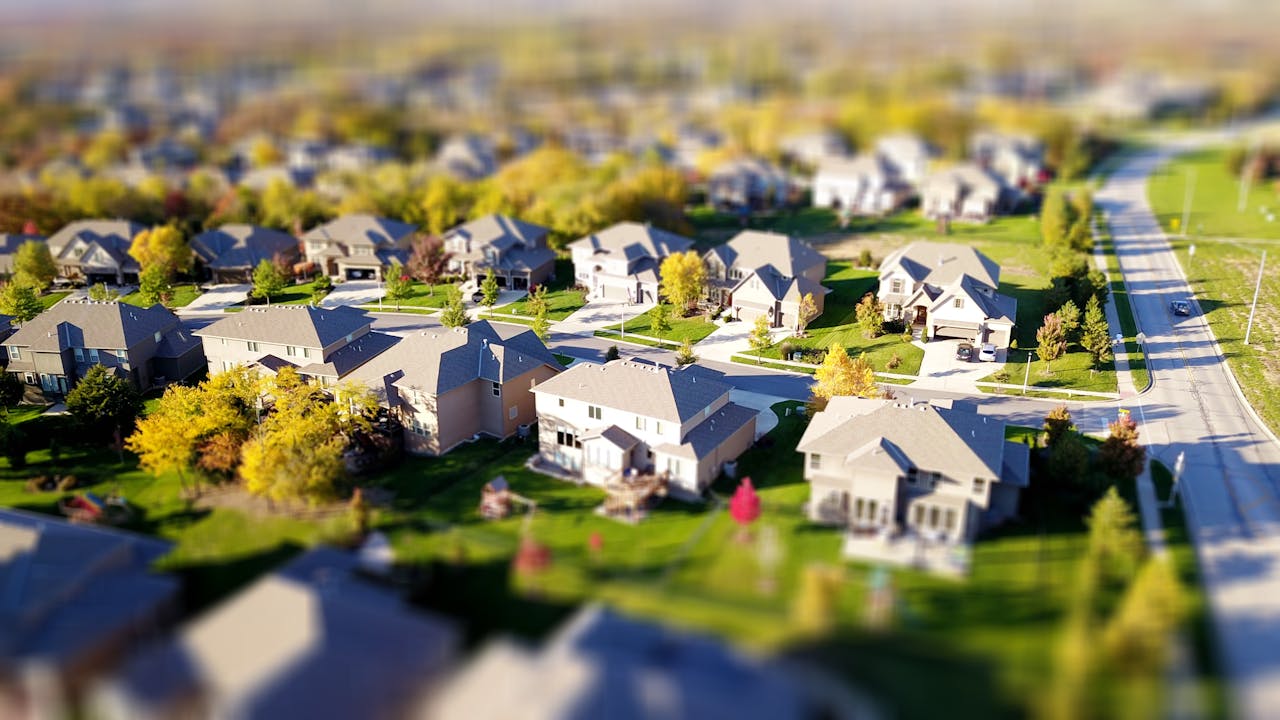 services-05 Tilt-shift aerial photo of a suburban neighborhood with green lawns and roads.
