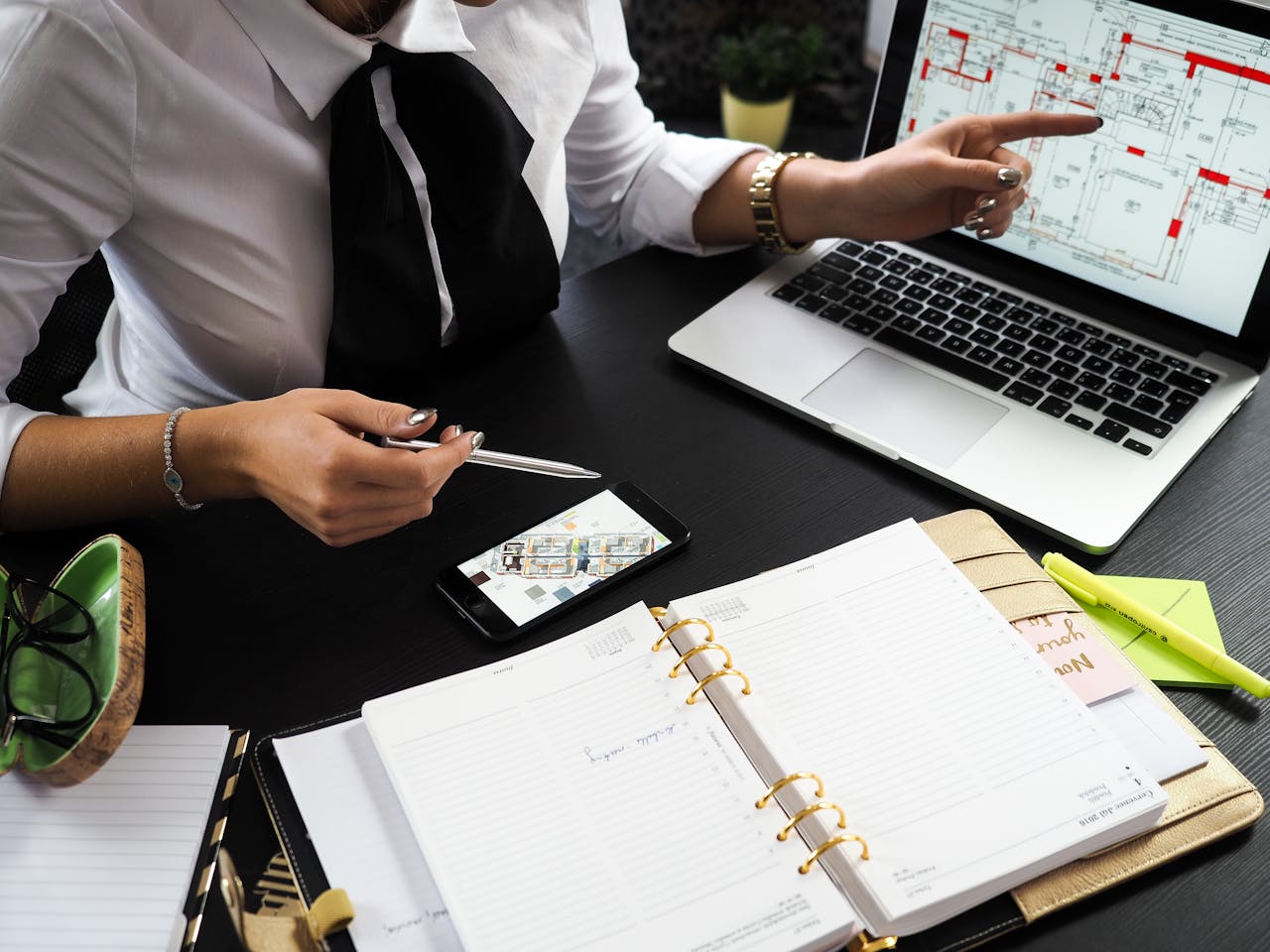 about-us A business professional working on real estate project plans using multiple devices in an office setting.