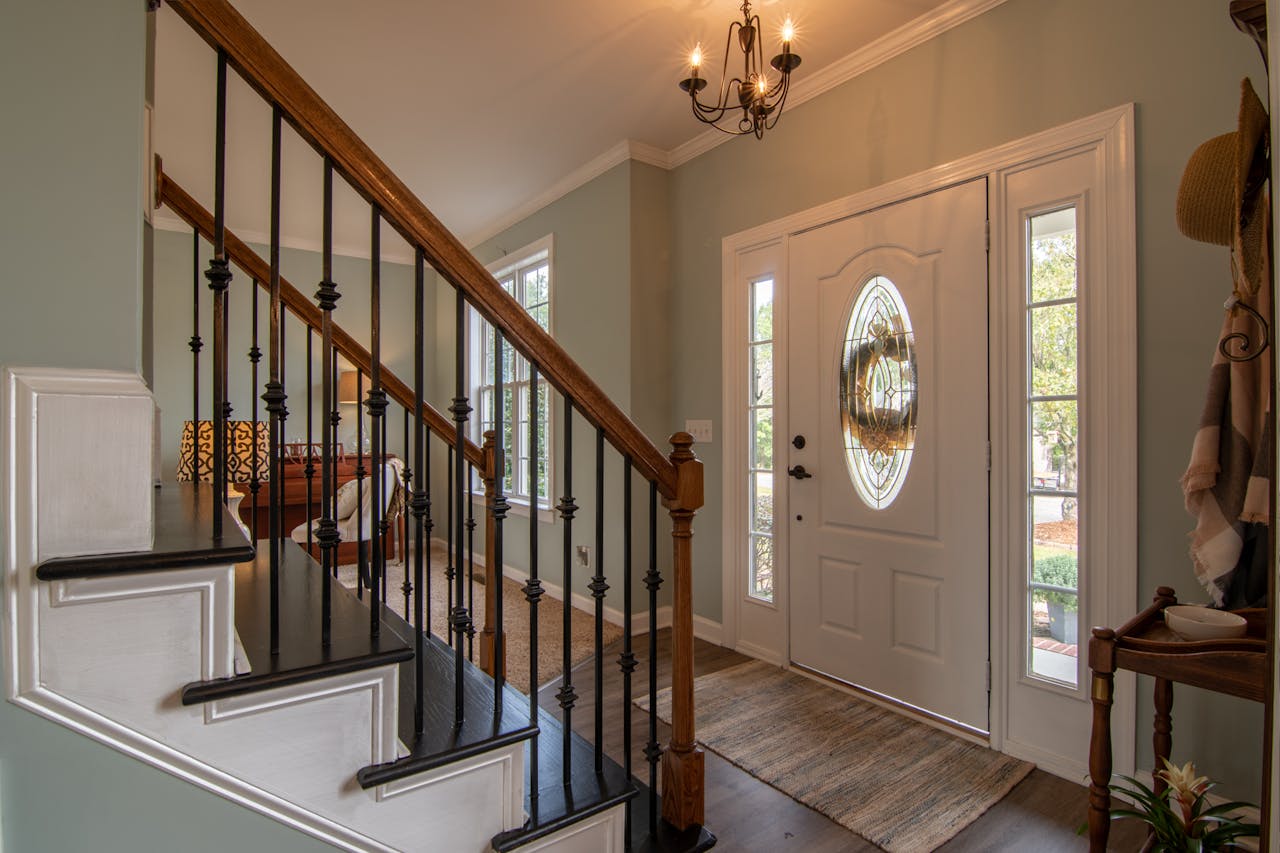 why-choose-us Inviting modern hallway with staircase, chandelier, and natural daylight.